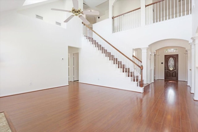 foyer featuring a towering ceiling, decorative columns, ceiling fan, and hardwood / wood-style flooring