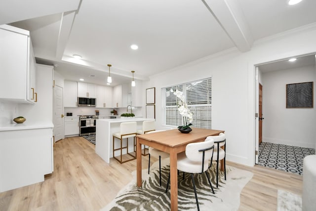 dining area featuring beam ceiling, ornamental molding, and light hardwood / wood-style floors