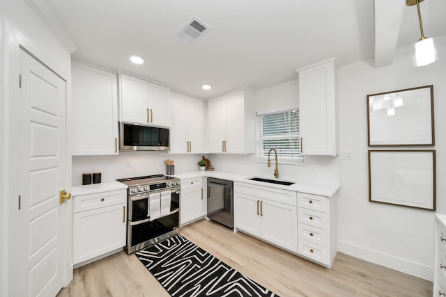 kitchen featuring pendant lighting, sink, light hardwood / wood-style flooring, stainless steel appliances, and white cabinets