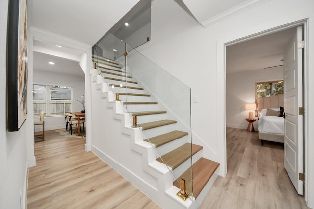 stairs featuring wood-type flooring and ornamental molding