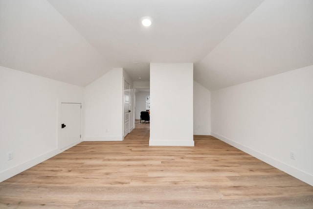 additional living space featuring vaulted ceiling and light hardwood / wood-style flooring