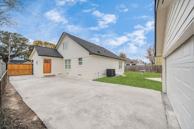 rear view of property featuring central AC unit, a patio area, and a lawn