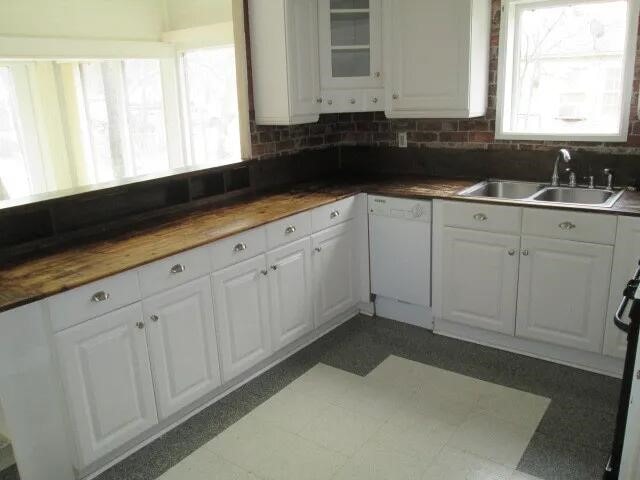 kitchen featuring wood counters, sink, white cabinetry, dishwasher, and decorative backsplash