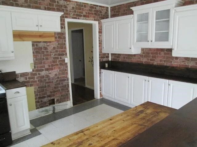 kitchen featuring brick wall and white cabinets