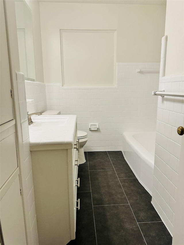 bathroom featuring tile walls, tile patterned flooring, vanity, toilet, and a bath