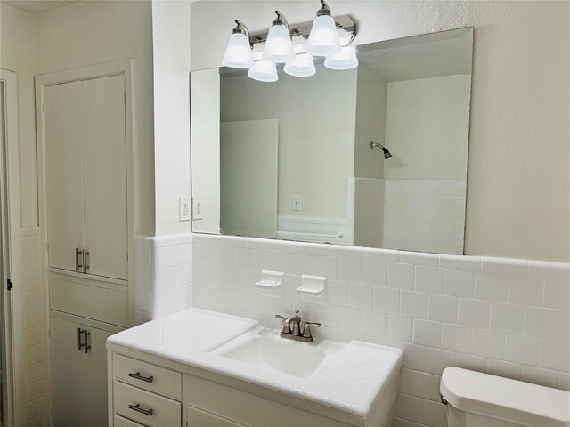 bathroom with vanity, tile walls, and toilet