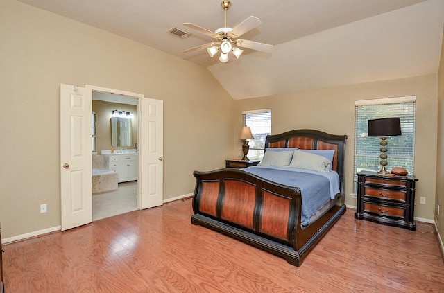 bedroom featuring light wood-type flooring, vaulted ceiling, ceiling fan, and ensuite bathroom