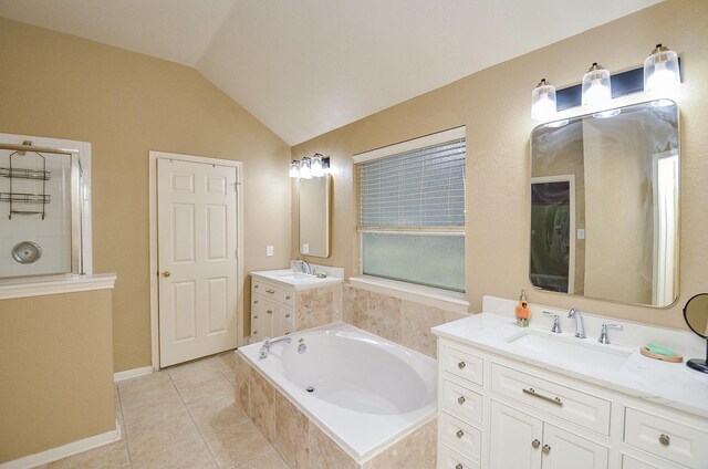 bathroom featuring vaulted ceiling, a relaxing tiled tub, tile patterned floors, and vanity