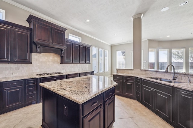 kitchen featuring sink, light tile patterned floors, a wealth of natural light, stainless steel gas cooktop, and decorative backsplash