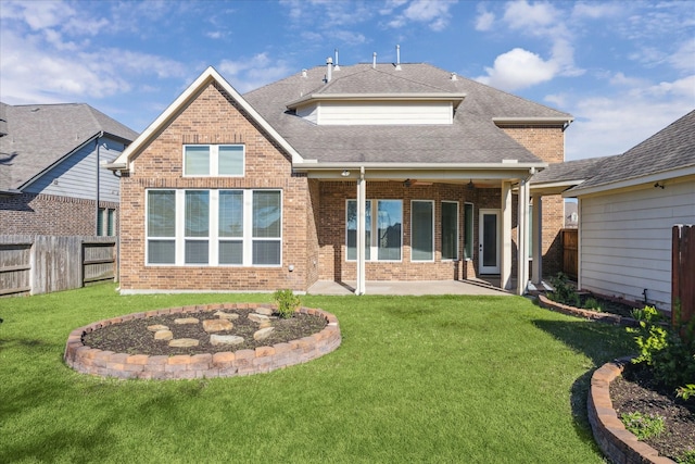 rear view of house with ceiling fan, a yard, and a patio