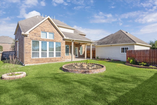 back of property with ceiling fan, an outdoor fire pit, and a yard