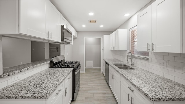 kitchen featuring sink, appliances with stainless steel finishes, light stone countertops, white cabinets, and decorative backsplash