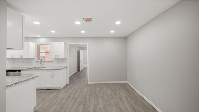 kitchen featuring sink, light stone counters, tasteful backsplash, white cabinets, and stainless steel dishwasher