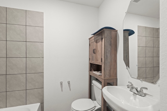 bathroom featuring sink, toilet, and a tub to relax in