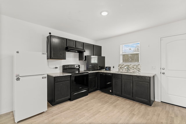 kitchen with light stone counters, light wood-type flooring, sink, and black appliances