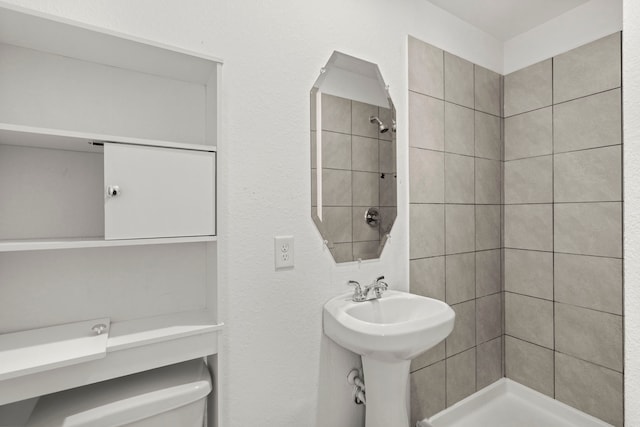 bathroom featuring tiled shower and toilet