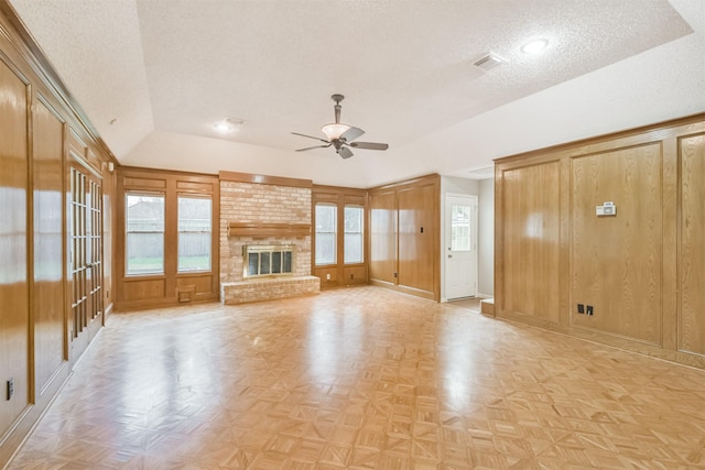 unfurnished living room featuring light parquet floors, vaulted ceiling, a brick fireplace, and ceiling fan