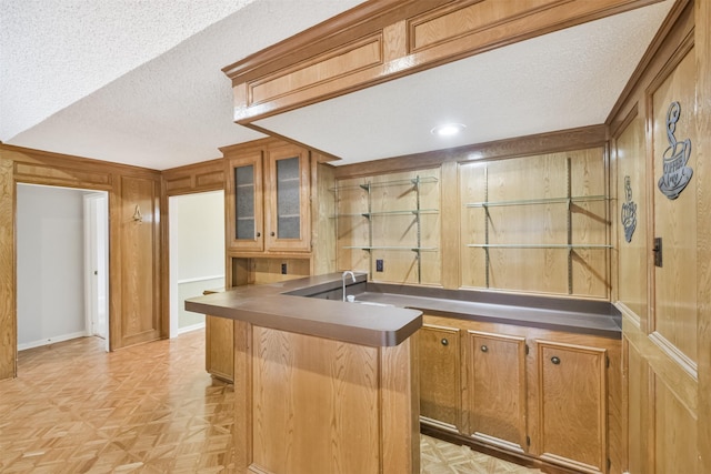 kitchen with a textured ceiling, wooden walls, and light parquet floors