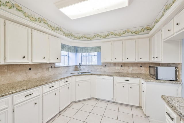 kitchen featuring white cabinetry, sink, light tile patterned floors, light stone counters, and white dishwasher