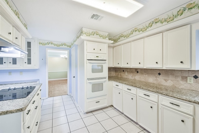 kitchen with white cabinetry, black electric stovetop, double oven, and light tile patterned floors