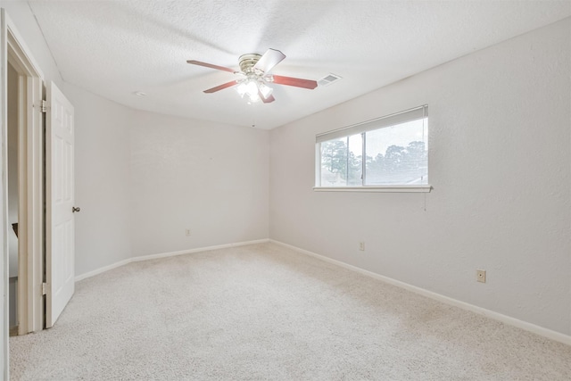 empty room with light carpet, a textured ceiling, and ceiling fan