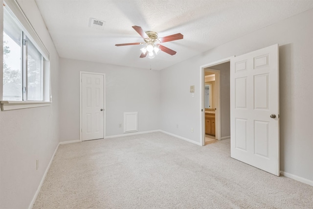 unfurnished room featuring a textured ceiling, light colored carpet, and ceiling fan