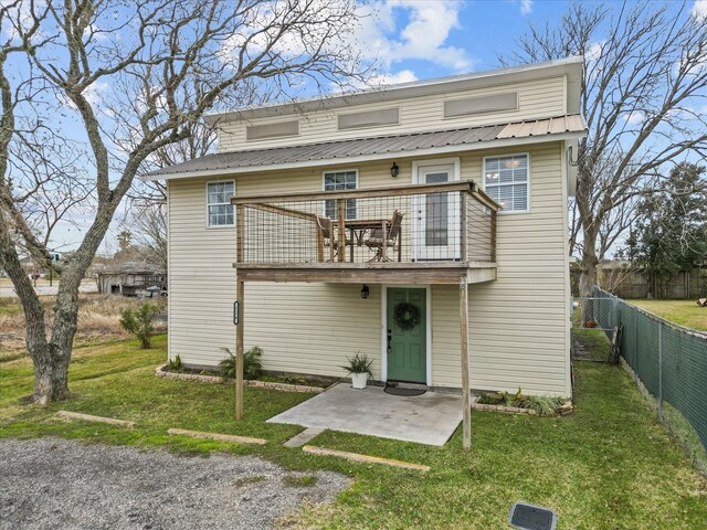 view of front of house featuring fence, a front lawn, metal roof, and a patio