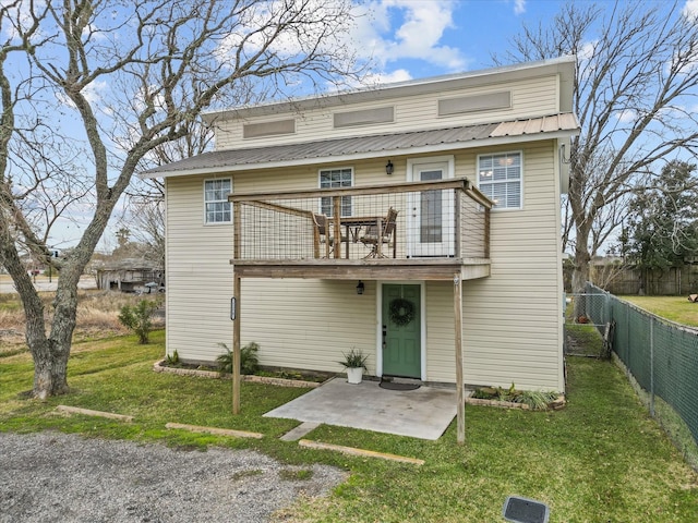 back of house featuring metal roof, a patio, a lawn, and fence private yard