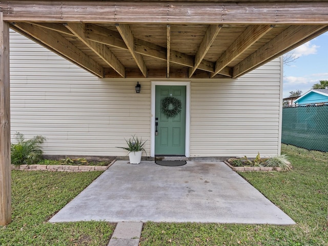 view of exterior entry featuring a patio area and fence