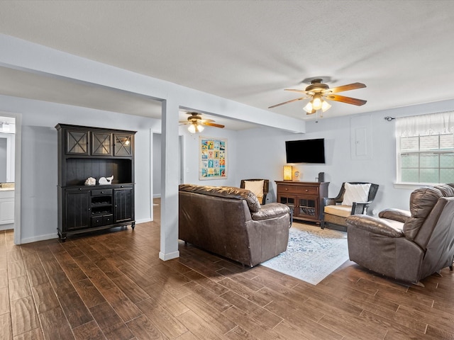 living area with dark wood-style floors, ceiling fan, a textured ceiling, and baseboards