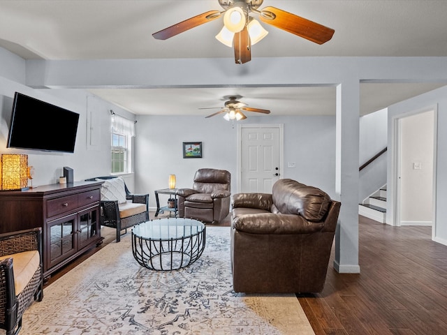 living area with stairs, wood finished floors, a ceiling fan, and baseboards