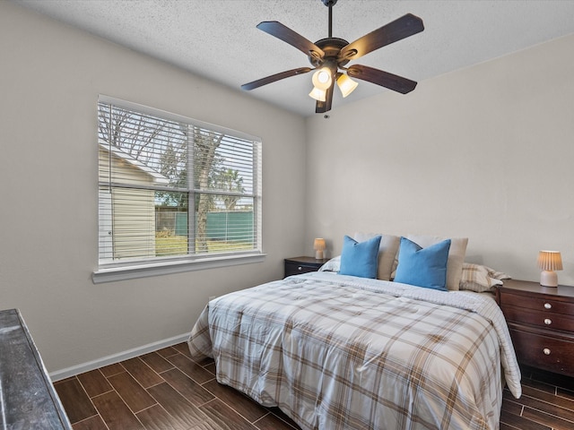 bedroom with a ceiling fan, wood tiled floor, a textured ceiling, and baseboards