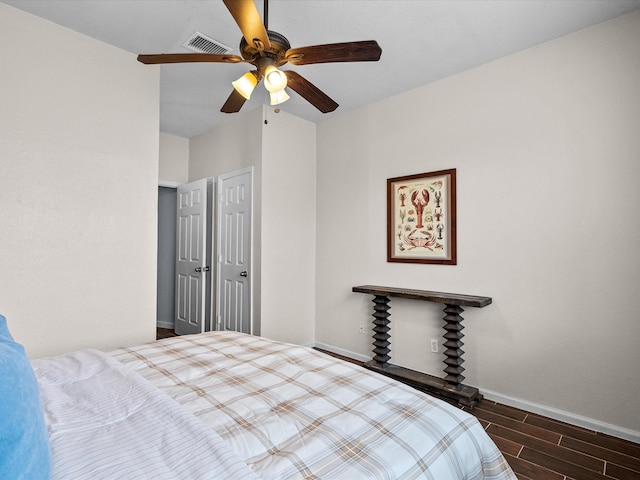 bedroom with a ceiling fan, wood finished floors, visible vents, and baseboards