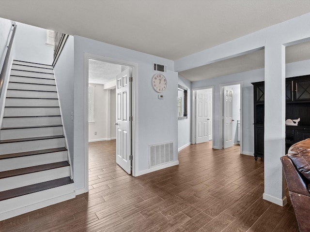 living area featuring stairs, dark wood-type flooring, and visible vents