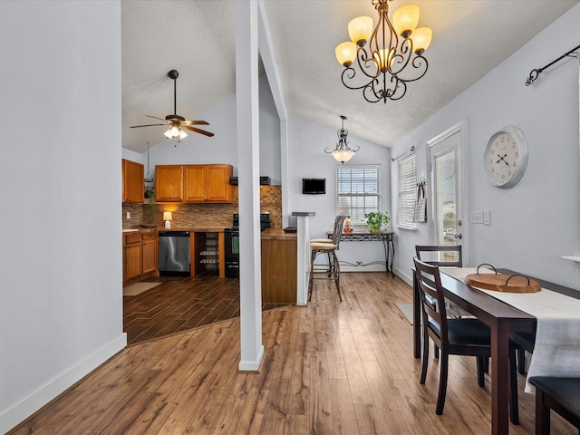 dining space featuring lofted ceiling, baseboards, a textured ceiling, and light wood finished floors