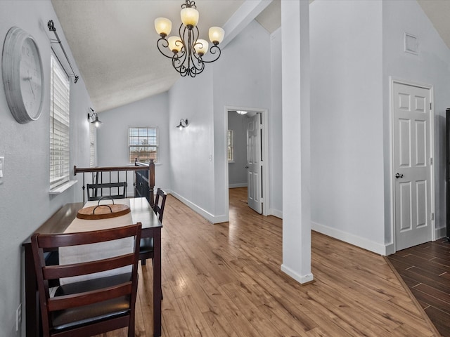 dining space featuring high vaulted ceiling, baseboards, wood finished floors, and an inviting chandelier