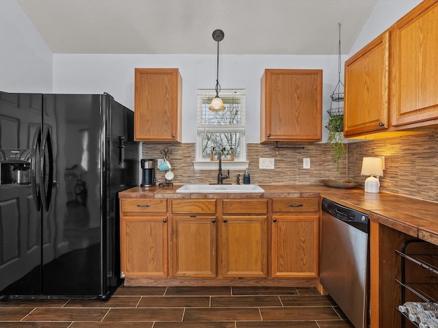 kitchen featuring dishwasher, backsplash, wood tiled floor, black fridge, and a sink