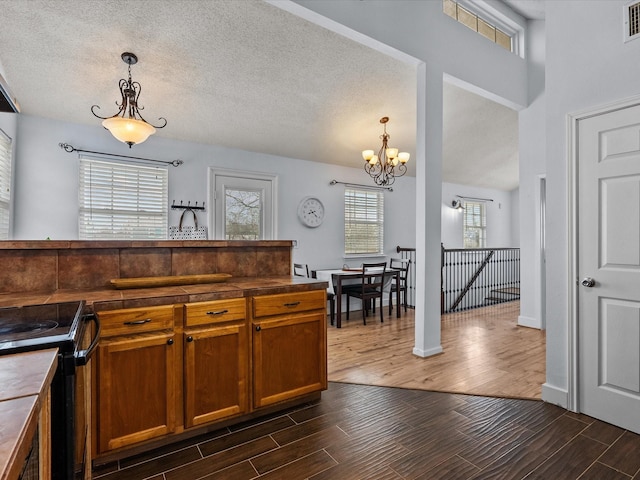 kitchen with black range with electric cooktop, visible vents, brown cabinets, and wood finish floors