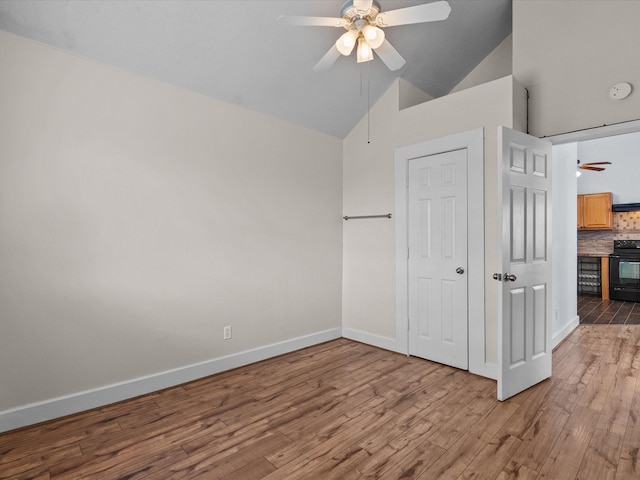 unfurnished bedroom featuring baseboards, high vaulted ceiling, a ceiling fan, and light wood-style floors