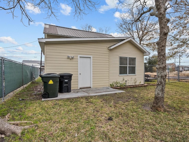 back of house featuring a fenced backyard, metal roof, a lawn, and a patio