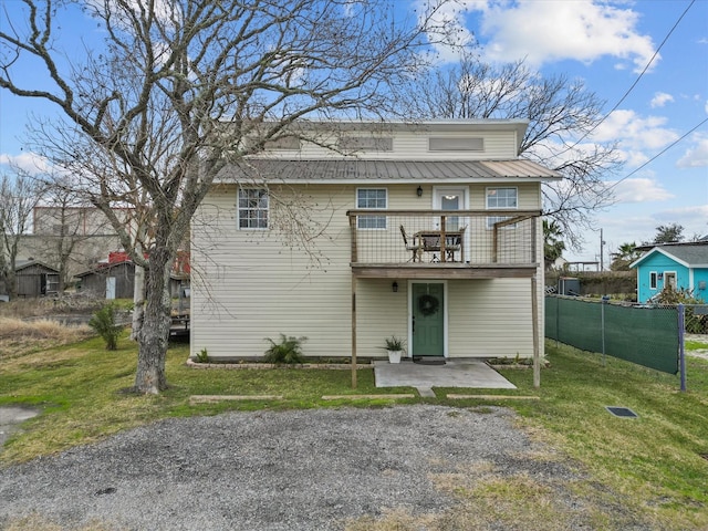 view of front facade with a patio area, metal roof, a front yard, and fence