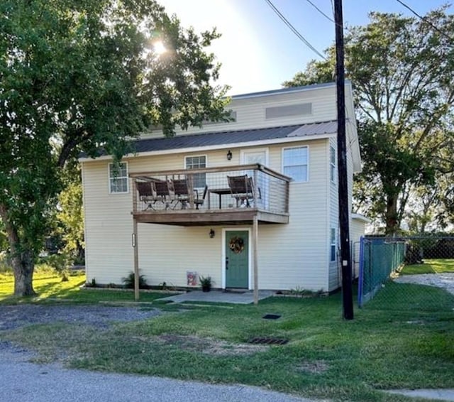 view of property with metal roof, fence, a wooden deck, and a front lawn