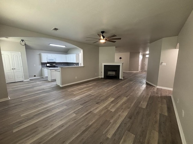 unfurnished living room with dark wood-type flooring, ceiling fan, and a textured ceiling