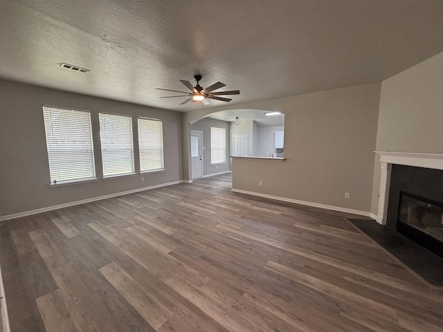 unfurnished living room with dark wood-type flooring, ceiling fan, and a textured ceiling