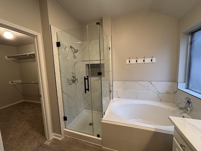 bathroom featuring lofted ceiling, vanity, plus walk in shower, and hardwood / wood-style floors