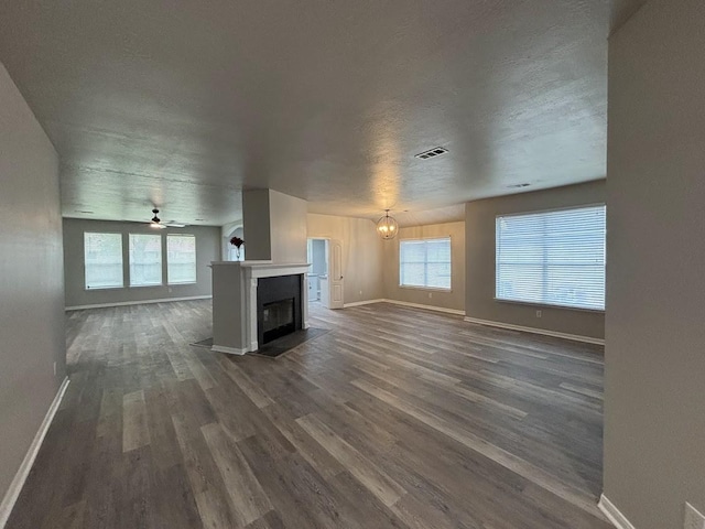 unfurnished living room with ceiling fan, dark hardwood / wood-style floors, and a textured ceiling