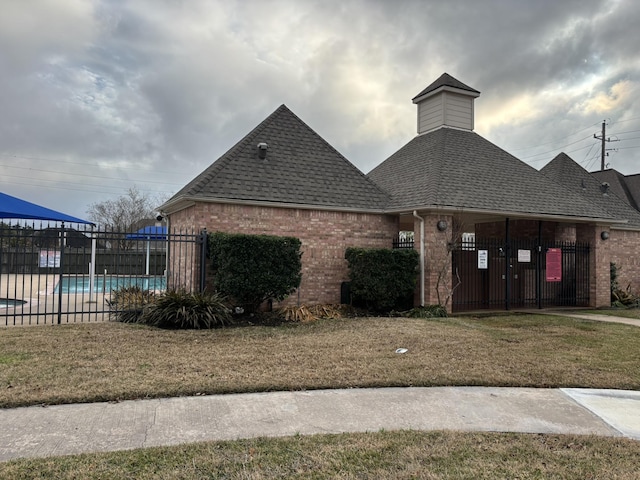 view of front of home with a community pool and a front lawn