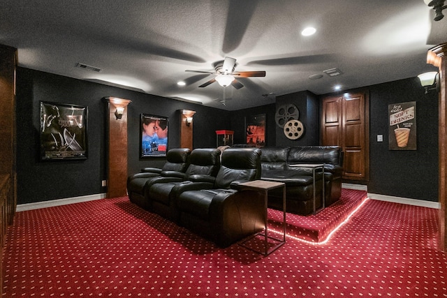 cinema with a textured ceiling, ceiling fan, and dark colored carpet