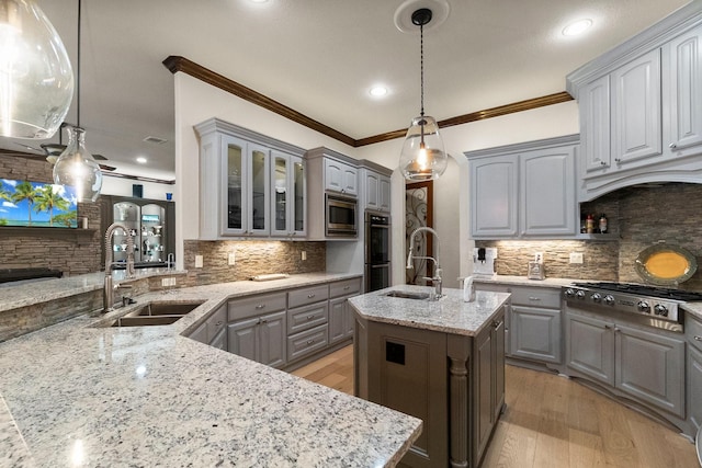 kitchen with a kitchen island with sink, sink, gray cabinetry, and hanging light fixtures