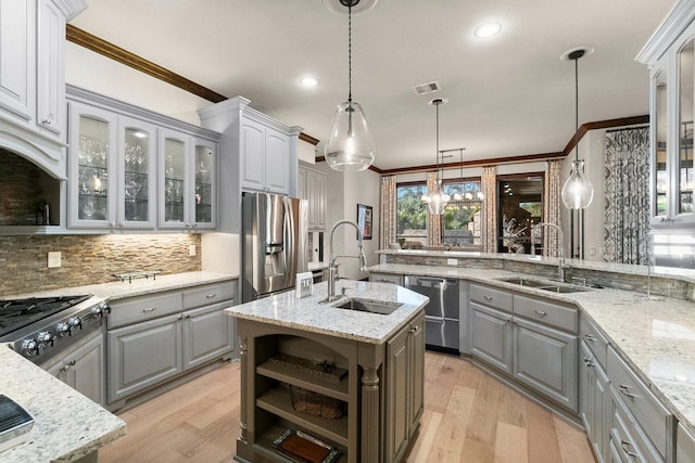 kitchen featuring sink, decorative light fixtures, a center island with sink, appliances with stainless steel finishes, and gray cabinets